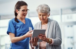 Talking,,Tablet,And,Nurse,With,Elderly,Woman,In,Clinic,For